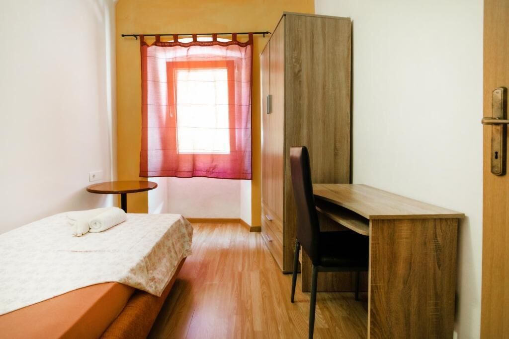 A small, compact room with a bed, a desk, and a chair.