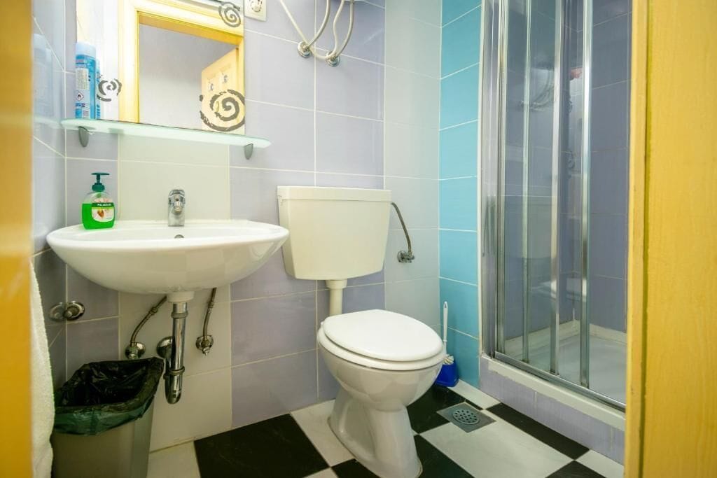 Un bagno con lavandino bianco, water e box doccia in vetro.
