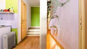 A narrow hallway with a radiator, a wooden door, and a staircase leading to a room with a green wall. - Hostel Martin (Koper)