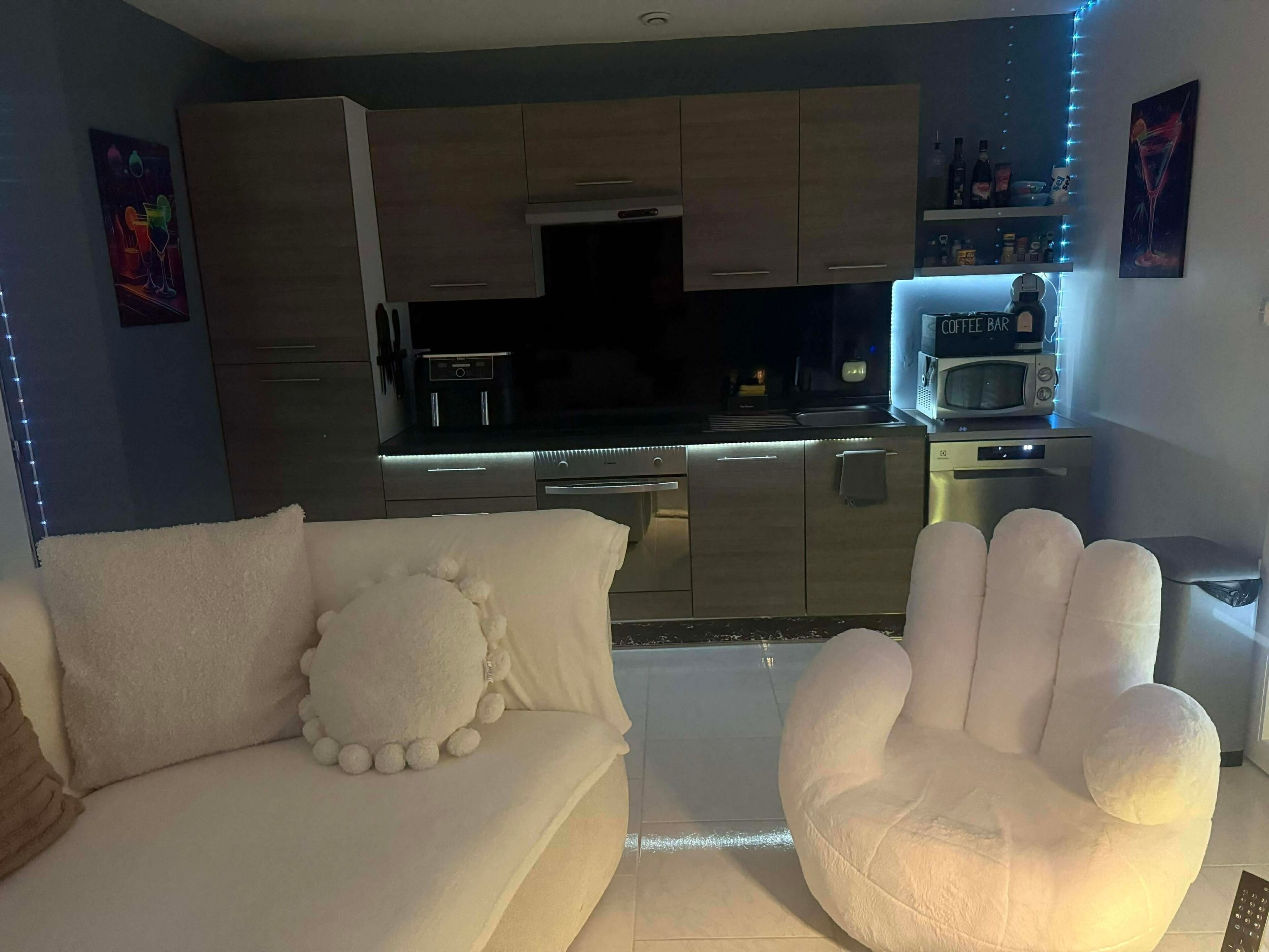 A modern kitchen with a built-in microwave, coffee machine, and a small refrigerator.