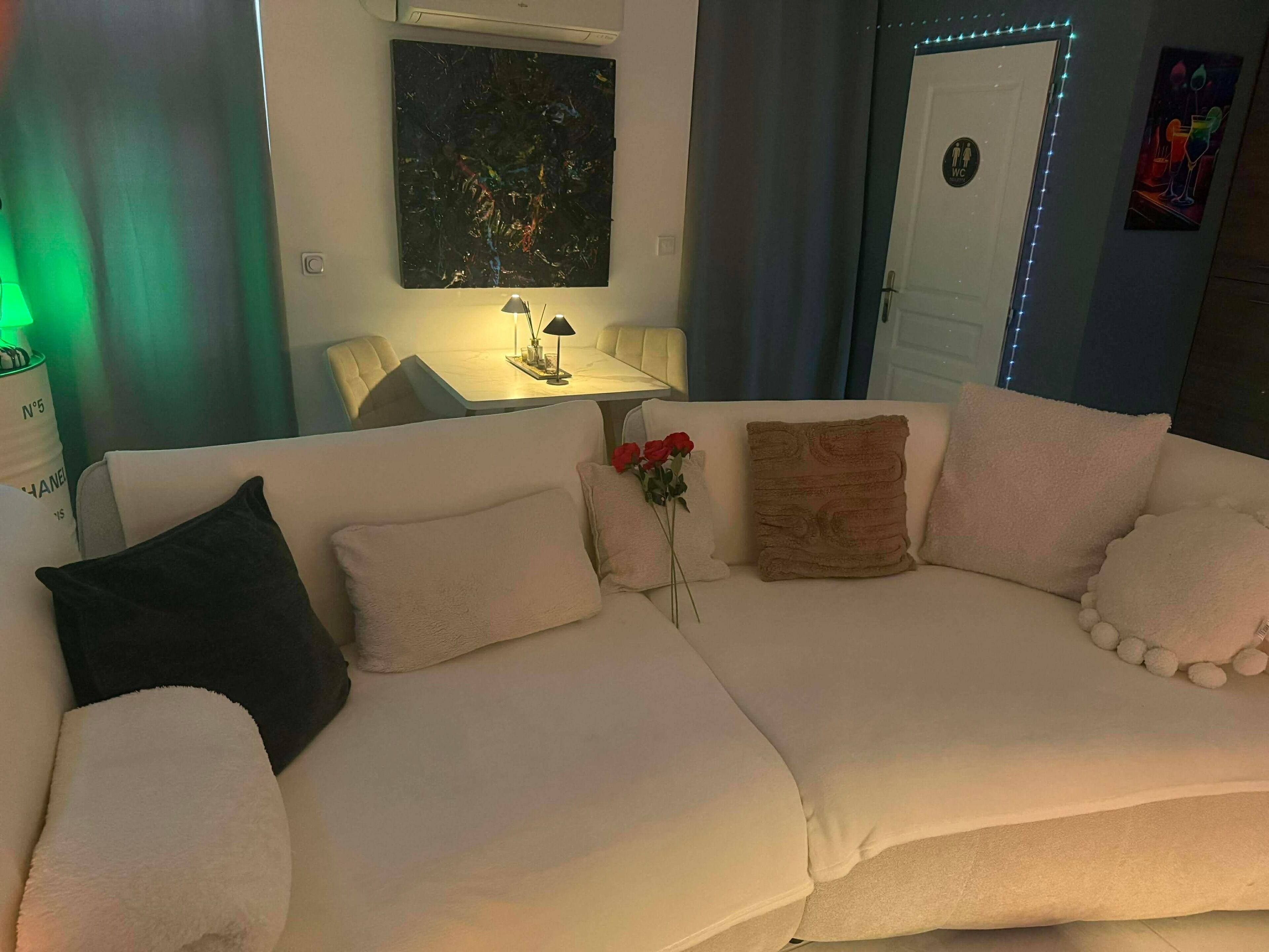 Una sala de estar moderna con un sofá, una mesita de noche con una lámpara y un cuadro en la pared.