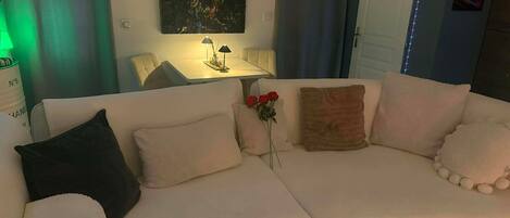 Una sala de estar moderna con un sofá, una mesita de noche con una lámpara y un cuadro en la pared.