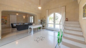 Un'ampia zona giorno con divano, tavolino e libreria. Una scala conduce a un altro livello.
