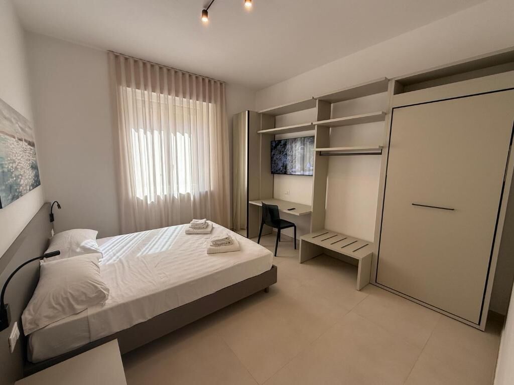 A modern bedroom with a bed, desk, chair, and wardrobe.