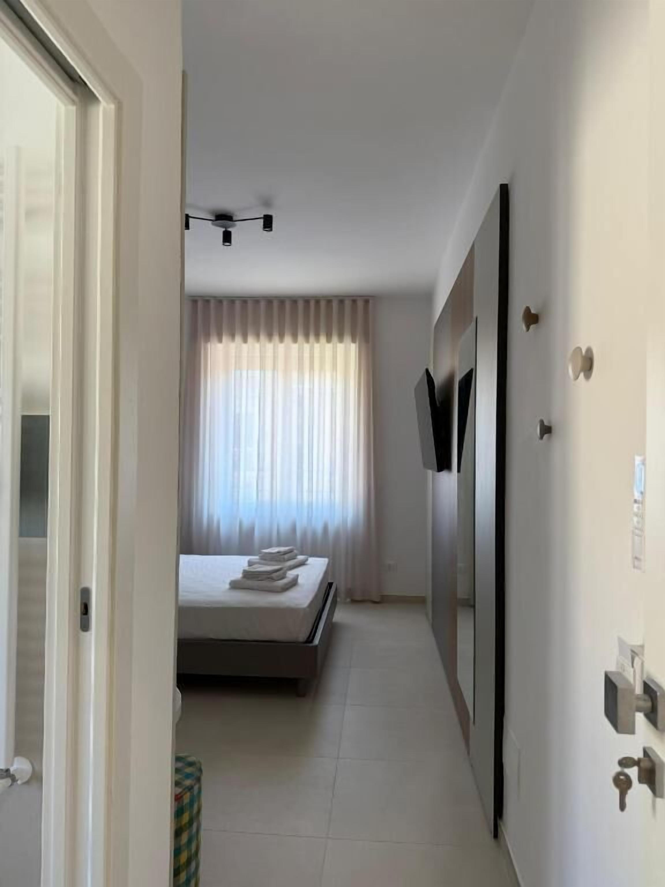 Una habitación de hotel con una cama, un televisor montado en la pared y una puerta con picaporte.