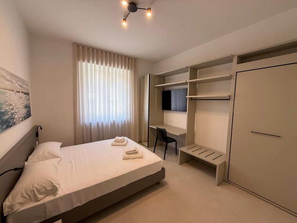 A modern bedroom with a bed, a desk, and a wardrobe.