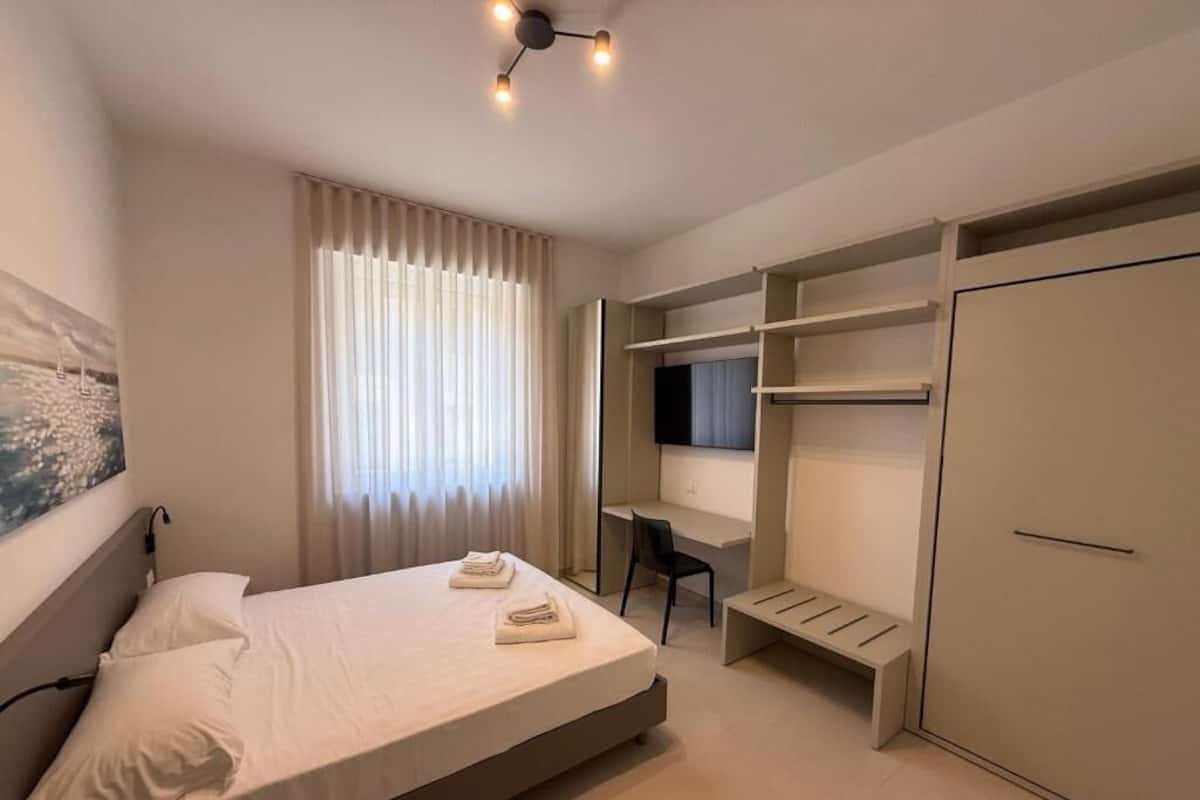 A modern bedroom with a bed, a desk, and a wardrobe.