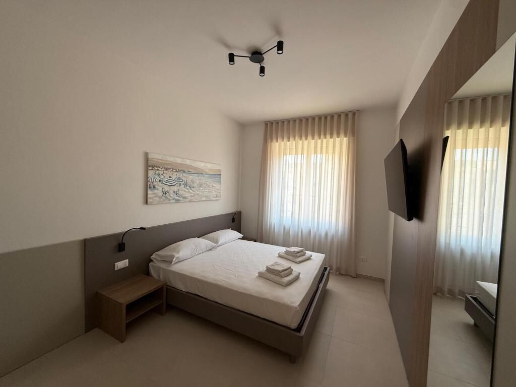 Una habitación de hotel moderna con una cama grande, mesitas de noche, un ventilador de techo y un televisor de pantalla plana.