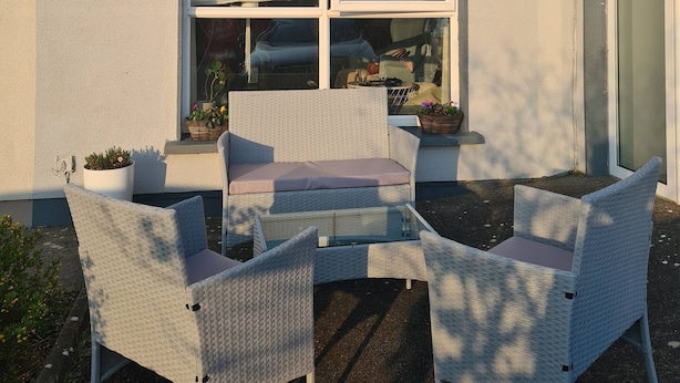 A two-story building with a patio area featuring wicker furniture and potted plants. - Cosy Home With Organic Garden (Athenry)