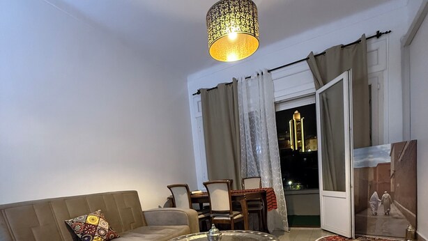 Uma sala de estar com sofá, mesa de centro redonda e luminária pendente.