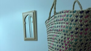 Uma cesta de vime sobre uma superfície escura, em frente a uma parede clara.