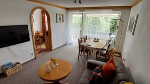 A living room with a TV, a dining table, and a sofa. - AllgäuZeit apartment with indoor pool & sauna & free WLAN (Missen-Wilhams)