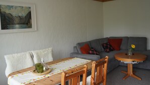 A dining area with a wooden table, chairs, and a painting of a mountain landscape on the wall. - AllgäuZeit apartment with indoor pool & sauna & free WLAN (Missen-Wilhams)