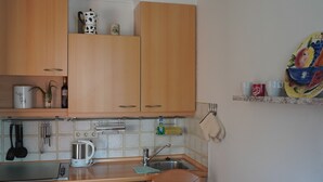 A compact kitchen with wooden cabinets, a coffee maker, and a dining table with placemats. - AllgäuZeit apartment with indoor pool & sauna & free WLAN (Missen-Wilhams)