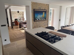Een moderne keuken met een centraal eiland, een eethoek met tafel en stoelen, en een woonkamer met een bank en salontafel.