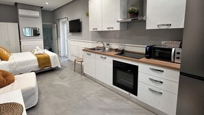 Una cucina moderna con mobili bianchi, forno integrato, microonde e lavello.