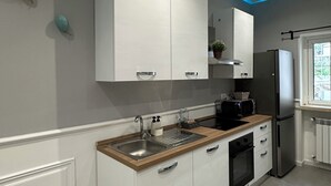 Una cucina moderna con mobili bianchi, un piano di lavoro in legno, elettrodomestici in acciaio inossidabile e una parete decorata in blu.