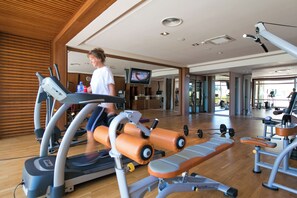 A gym with cardio equipment, weight machines, and a television screen. - Hotel Palas (Petrovac)