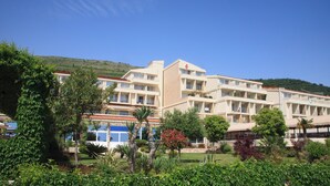 Un hotel de varios pisos con techo plano, rodeado de vegetación exuberante y un paisaje montañoso.