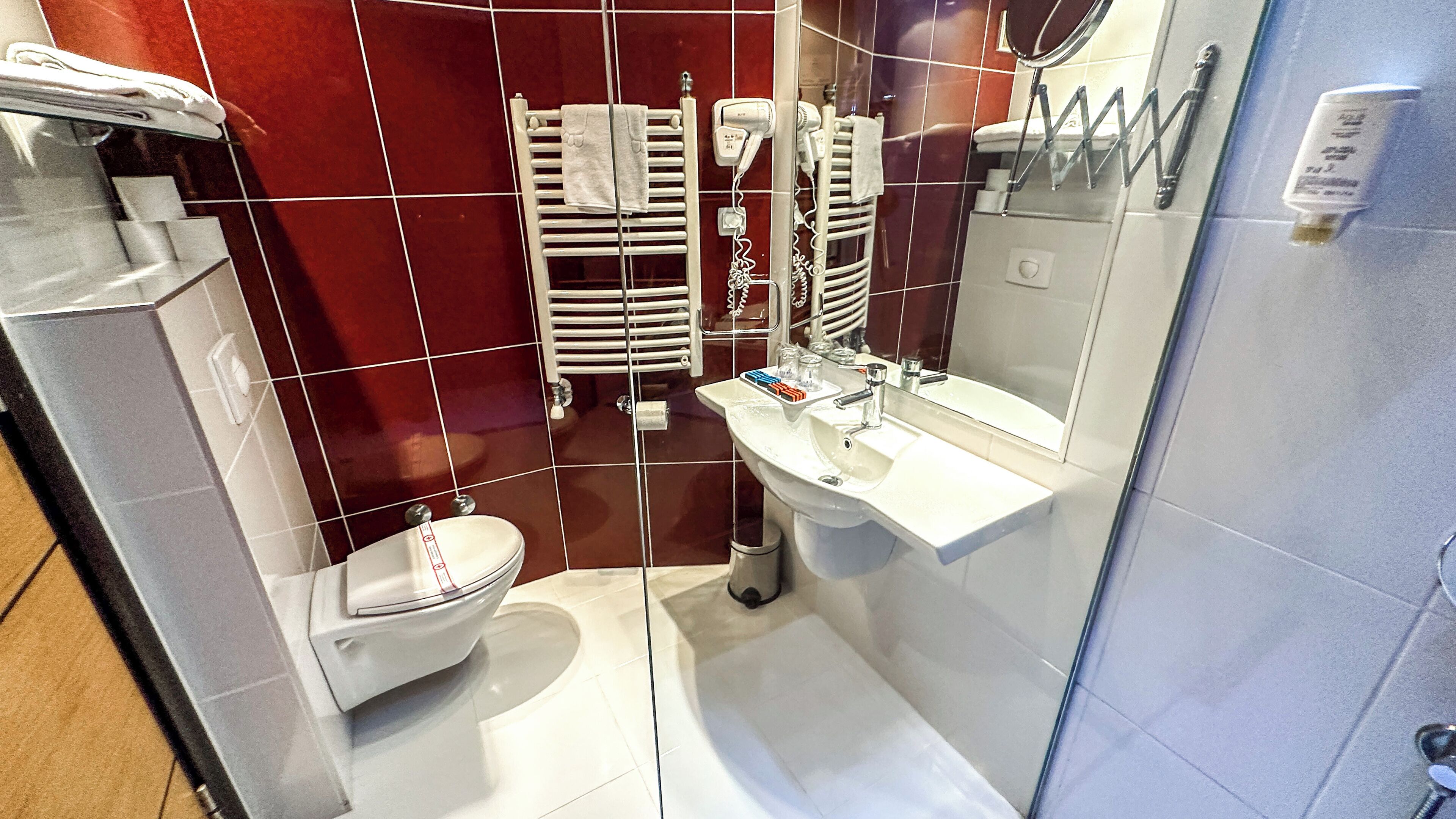 A bathroom with a white sink, mirror, and toilet. There are towels and a hairdryer on the wall.