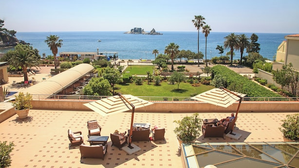Una terraza en la azotea con mobiliario exterior, una piscina y vistas al mar y una pequeña isla.