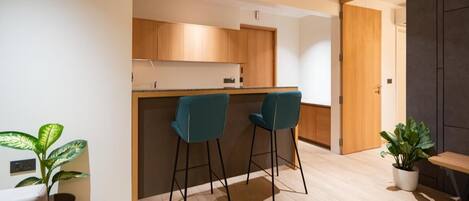 A modern kitchen with wooden cabinets, a central island, and two teal bar stools.
