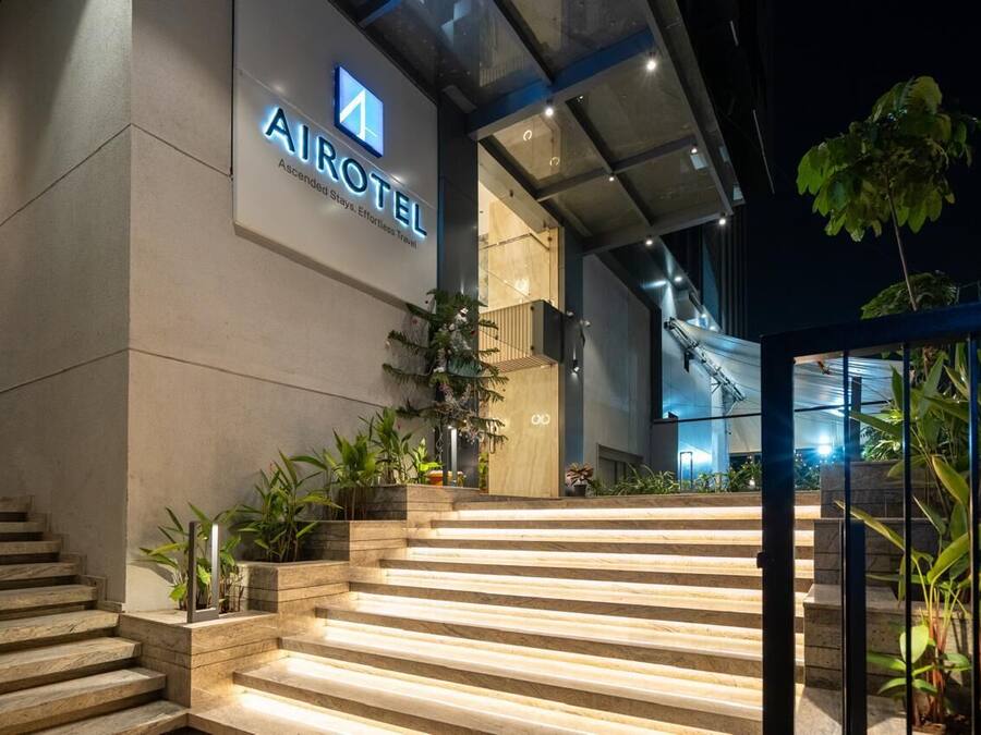 Una entrada de hotel moderna con un cartel que dice "AIROTEL" y una escalera que conduce a la entrada.