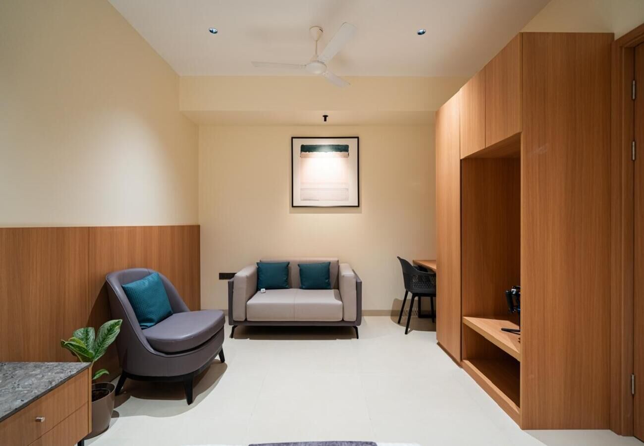 A modern room with a sofa, a chair, a desk, and built-in wooden shelving.