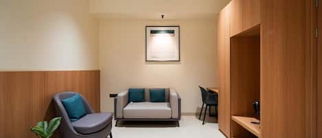 A modern room with a sofa, a chair, a desk, and built-in wooden shelving.