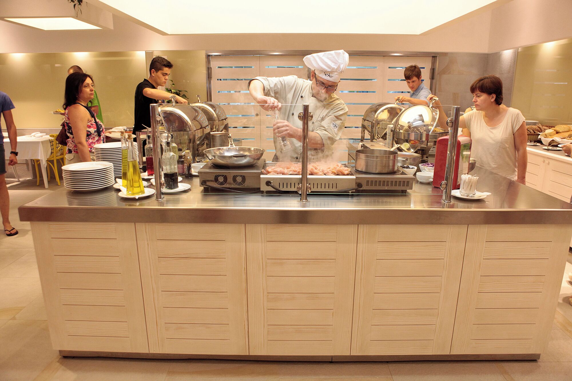 A buffet setup with multiple serving stations, a central cooking area, and a variety of food items and condiments.