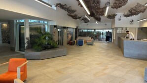 En modern entréhall med en receptionsdisk, sittgrupper och en glasvägg.