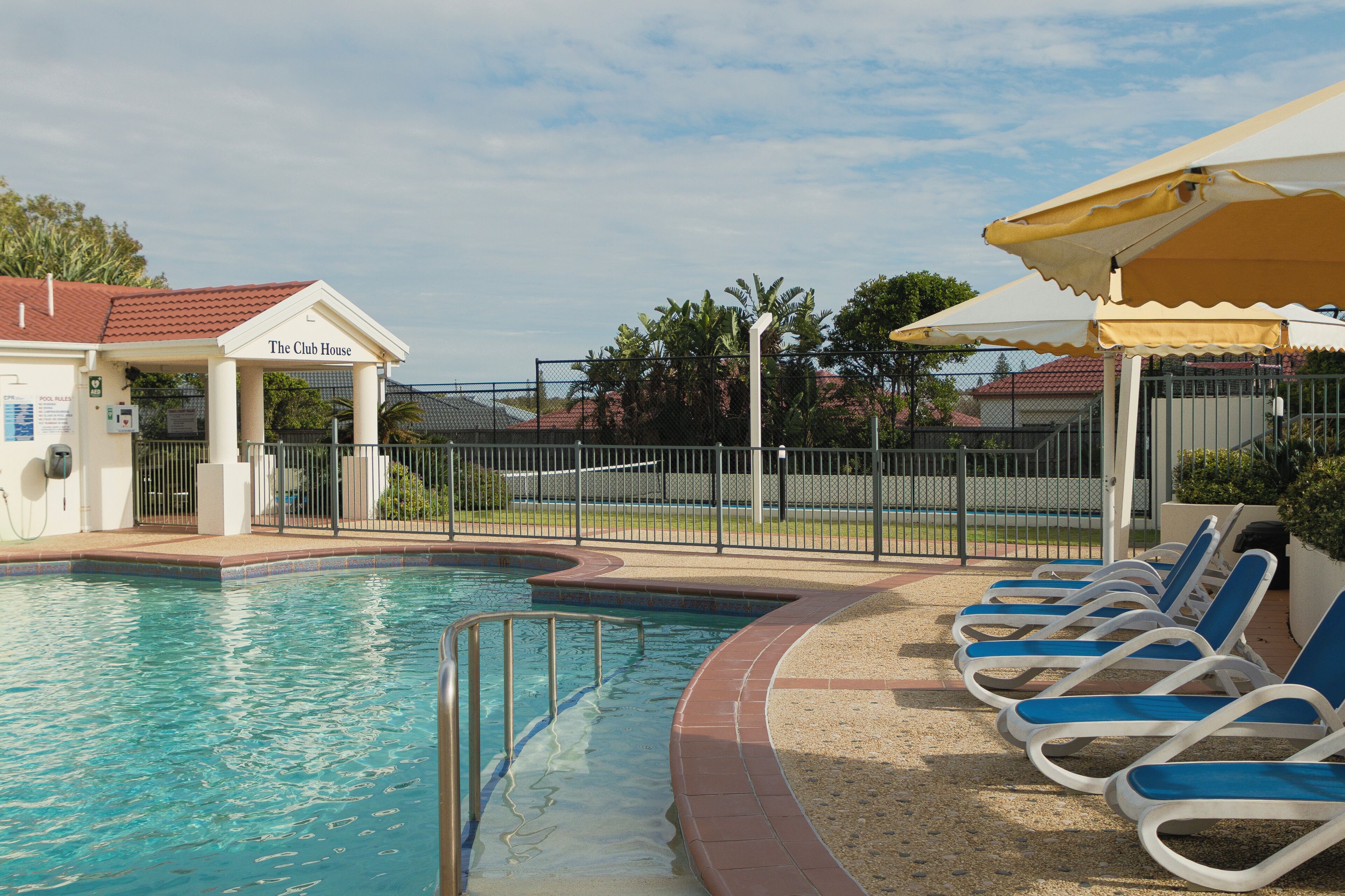 Ein Schwimmbecken mit Liegestühlen und einem überdachten Bereich, der "The Club House" heißt.