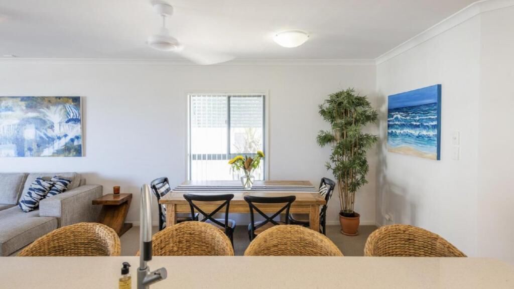A dining area with a wooden table, black chairs, and a potted plant.