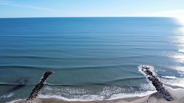Ein Strand mit ruhigem Wasser und einer felsigen Küstenlinie.