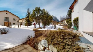 Un patio cubierto de nieve con edificios, árboles y una montaña al fondo.