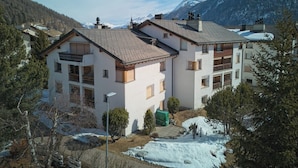 Un edificio de varios pisos con balcones, rodeado de nieve y montañas.