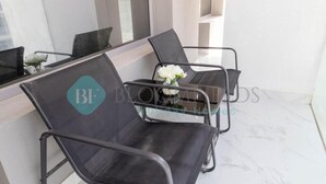 Una hall d'albergo moderna con pavimento in marmo, un tavolo in vetro e due sedie nere con logo color acquamarina.