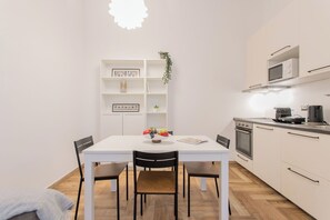 A modern kitchen with white cabinetry, a microwave, a coffee maker, and a dining table with chairs. - Residence in Como with 1 bedrooms sleeps 4 (Como)