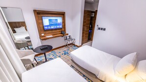 A hotel room with two beds, a desk with a computer, a TV mounted on the wall, and a wardrobe. - Jasmine Garden Hotel Makkah (Makkah)
