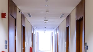 A long, narrow hotel corridor with wooden doors on both sides, a patterned floor, and a ceiling with recessed lighting. - Jasmine Garden Hotel Makkah (Makkah)