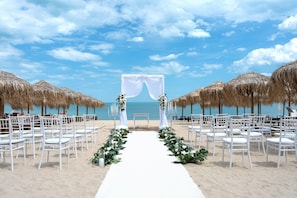 A beach wedding setup with a white aisle, chairs, and a canopy. - Casa dell'Eleganza Event Hall & Hotel (Kranevo)