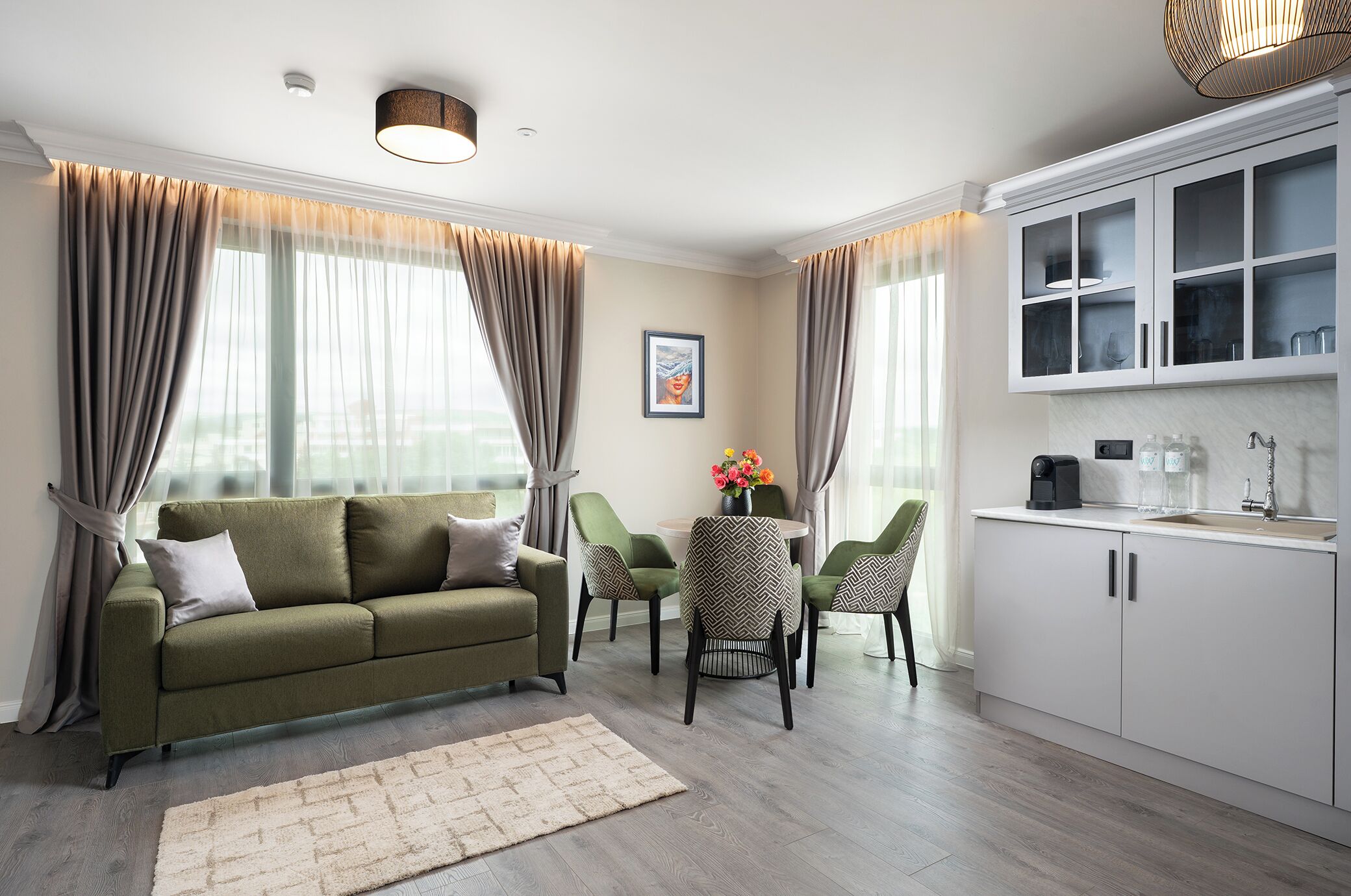 A modern living room with a sofa, chairs, a coffee table, and a kitchen area with cabinets and a sink.