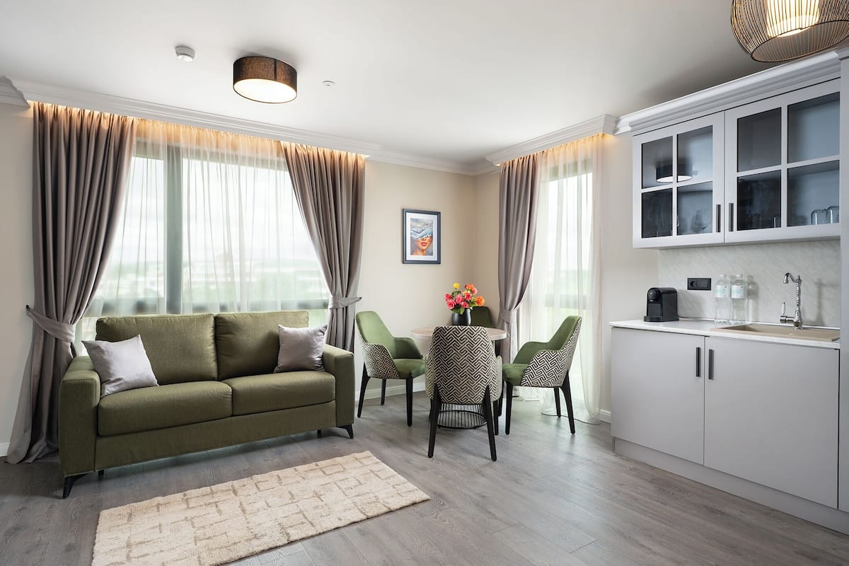 A modern living room with a sofa, chairs, a coffee table, and a kitchen area with cabinets and a sink.