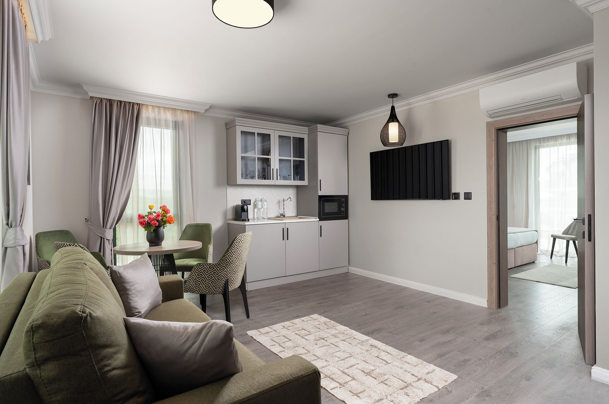 A modern living room with a sofa, a dining table, and a kitchen area with cabinets and a microwave.