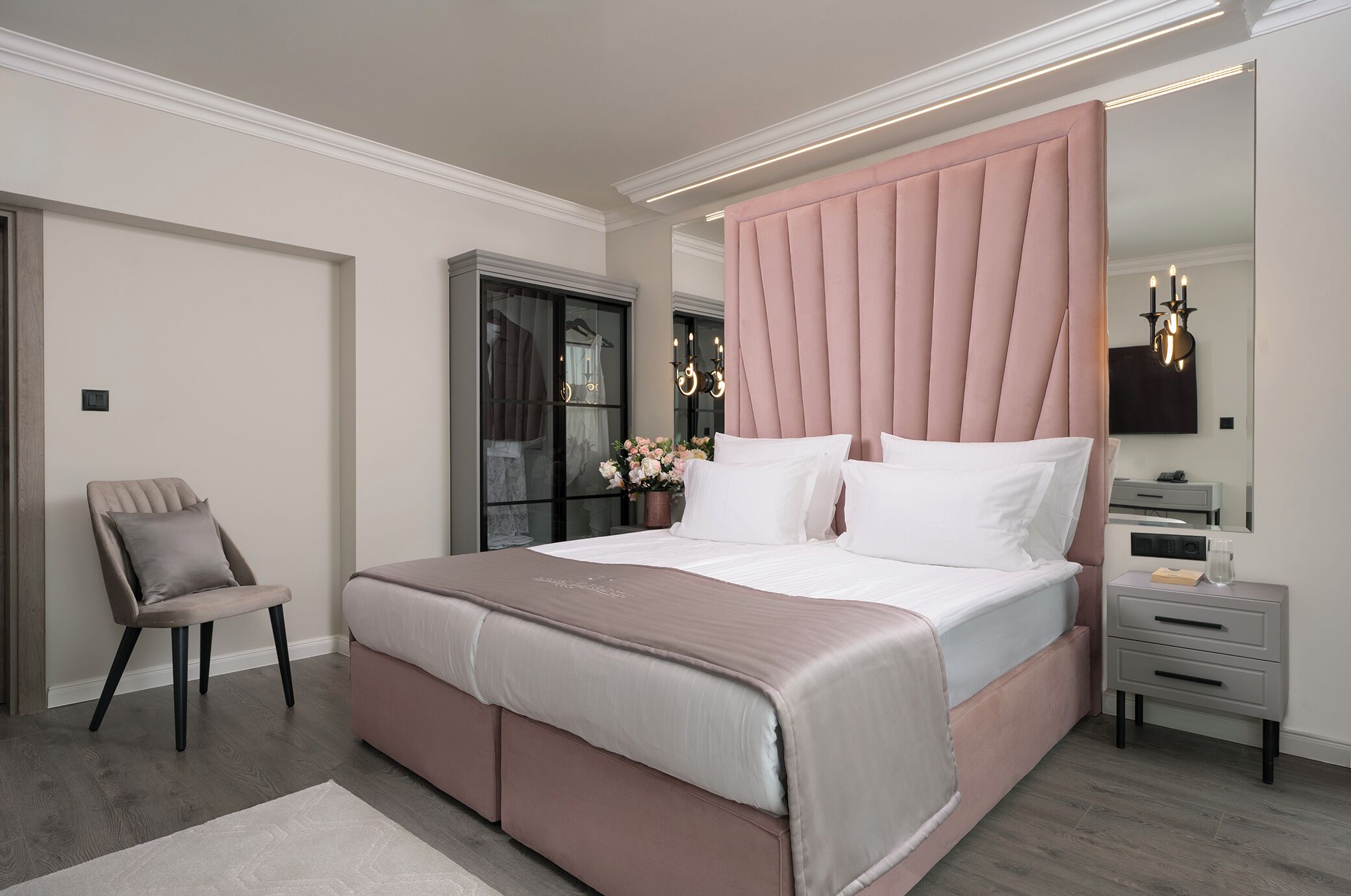 Un dormitorio con una cama grande, una mesita de noche, una silla y un armario.