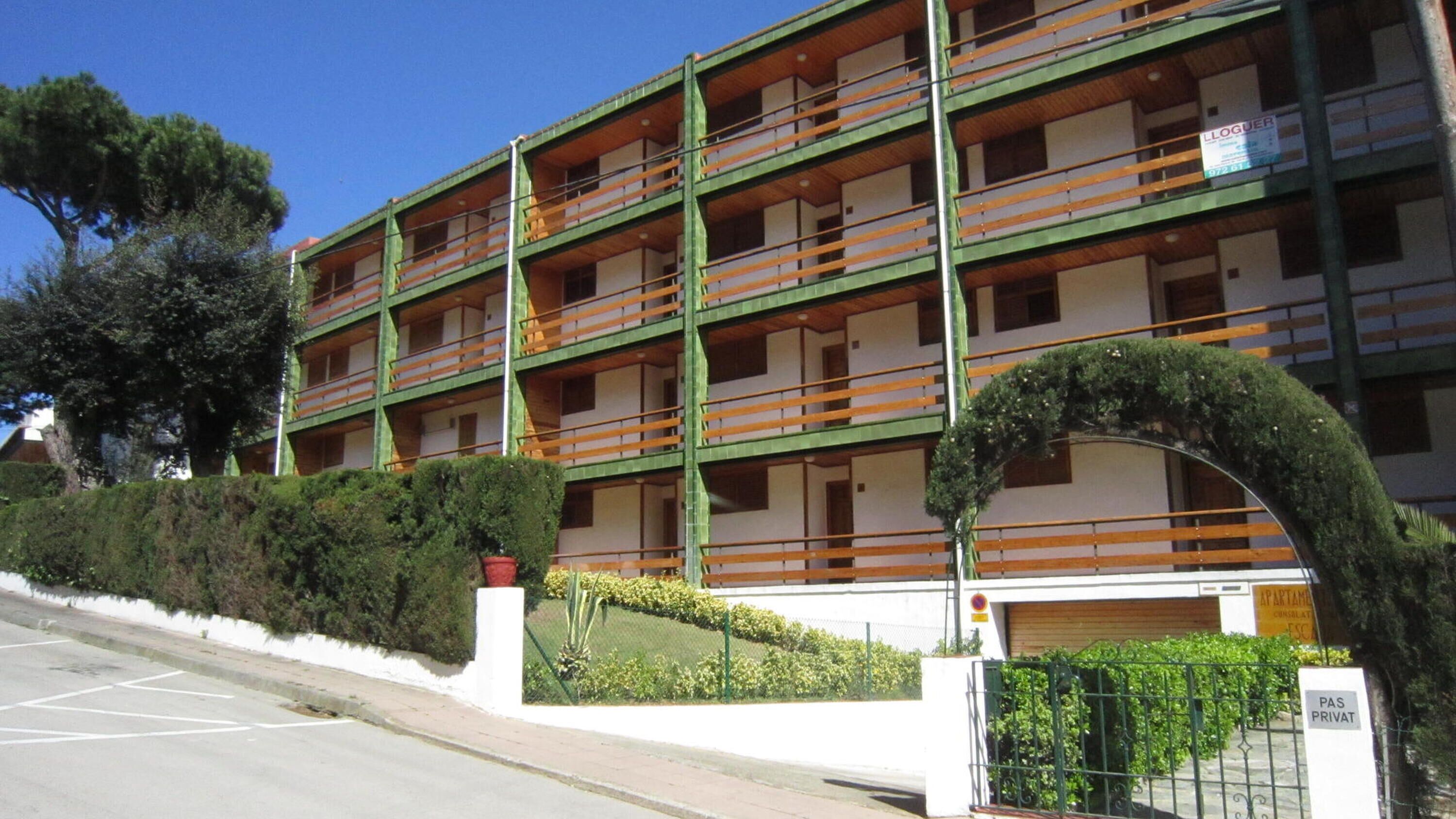 A multi-story building with balconies, a gated entrance, and a sign indicating private access.