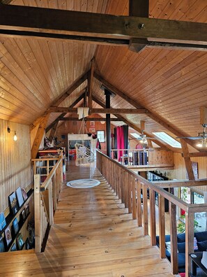 Un intérieur en bois avec un plafond haut, un escalier et une vue sur l’extérieur.