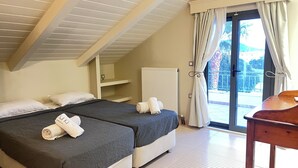 Een slaapkamer met twee bedden, een radiator, een houten tafel en een balkon met gordijnen.