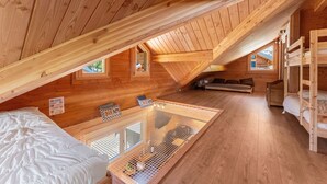 Ein Holzinterieur mit einem Etagenbett, einer Couch, einem kleinen Tisch und einem Fenster.
