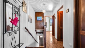 Un pasillo con una escalera, una puerta de madera y un techo con diseño radial.